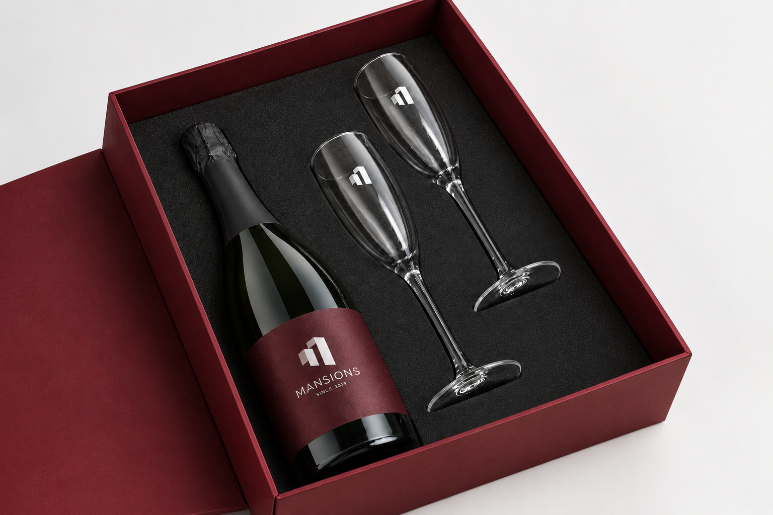 Mansions — Estuche burdeos abierto con la botella personalizada y las dos copas serigrafiadas.
